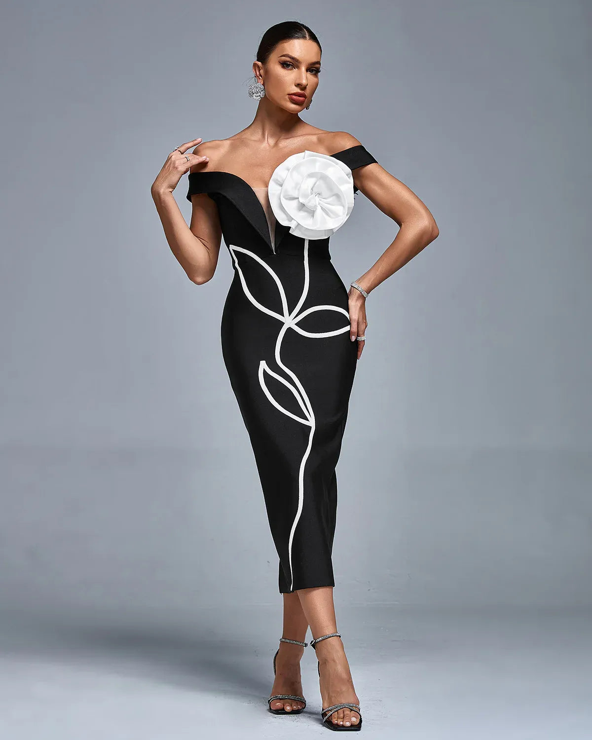Photo of the Midi Dress Liria by Majestique in black, featuring off-shoulder floral bust detail, white embroidery, and deep V illusion neckline.